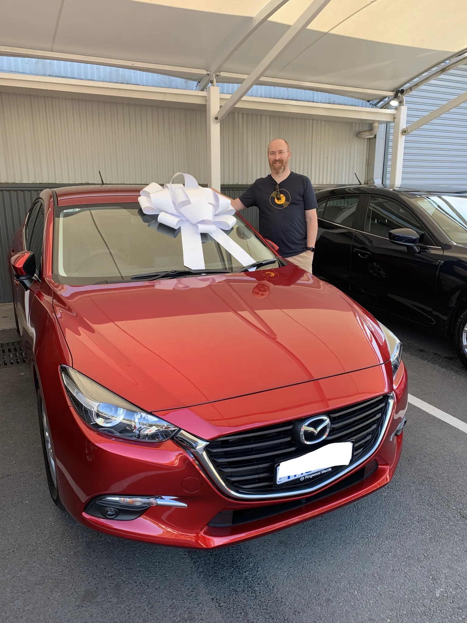 A man standing next to a car with a bow on it