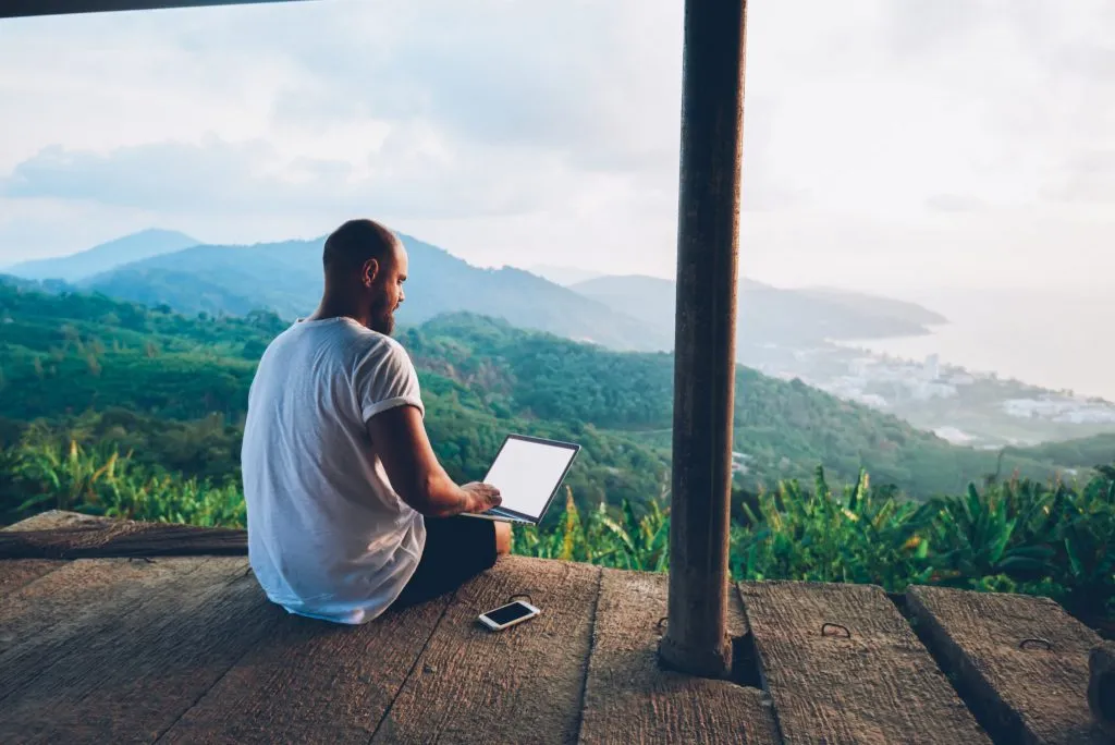 A man working on his laptop on his porch